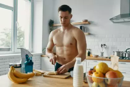 Confident fit man preparing healthy food while standing at the kitchen